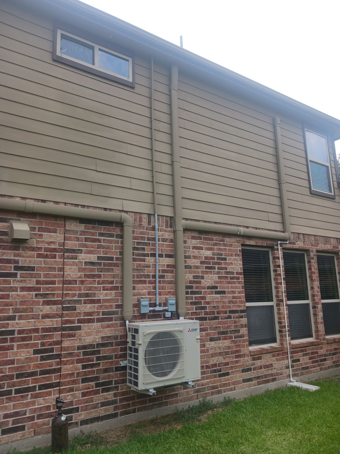 Outdoor multi-zone ductless mini split installation on a Houston home with multiple wall penetrations for targeted cooling