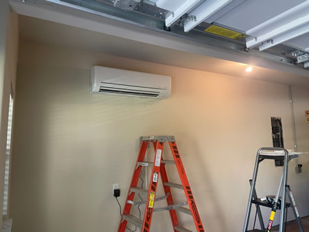 Technician mounting a wall mounted ductless ac in a houston garage